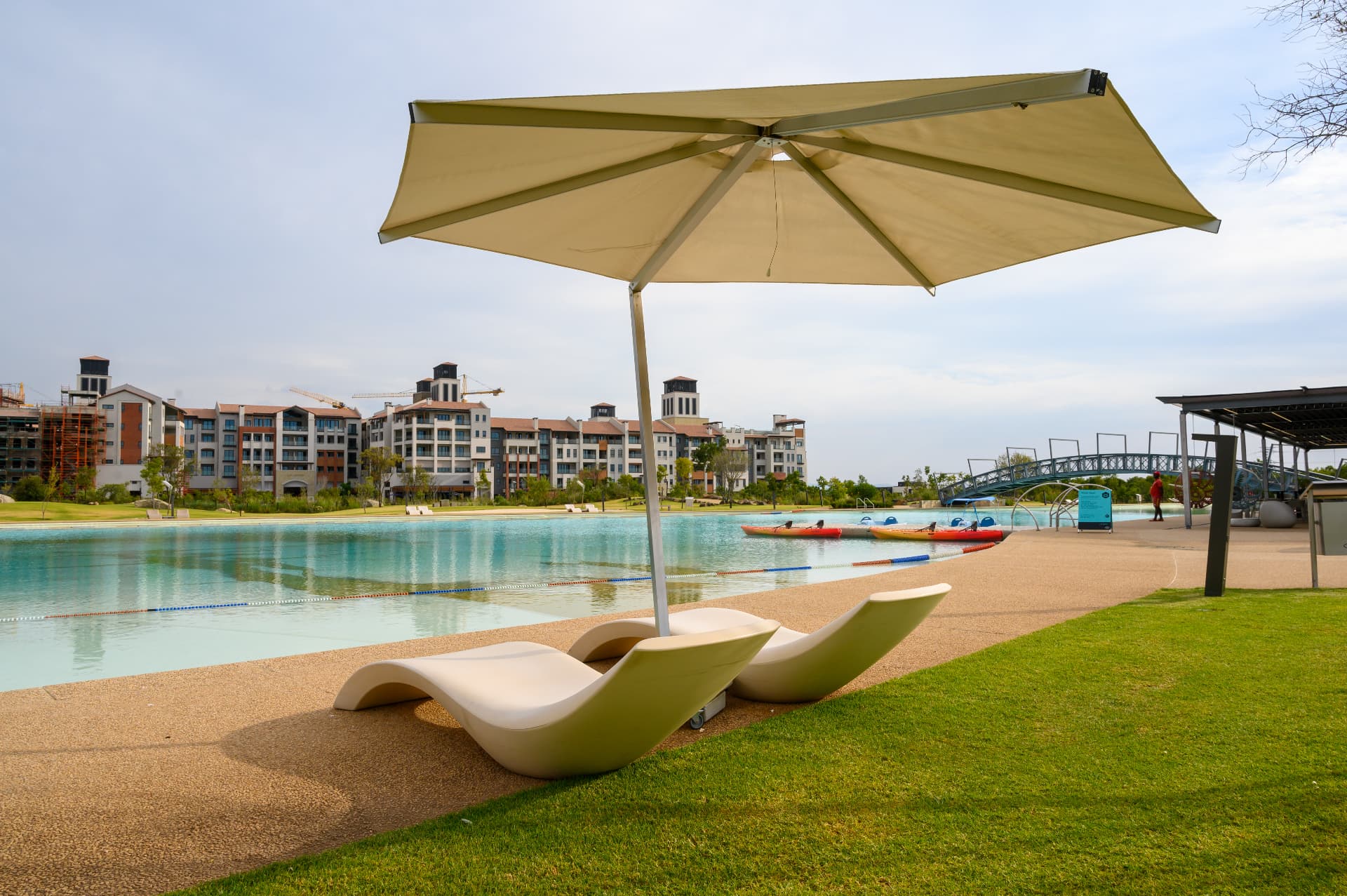 Steyn City lagoon with sun loungers, kayaks and an arched footbridge