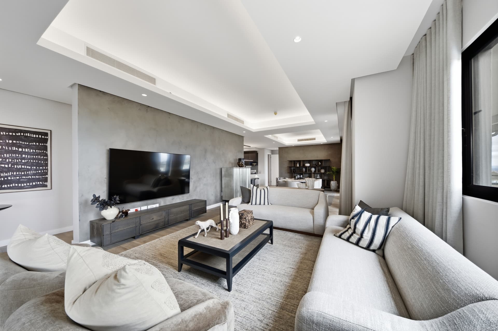 Living room with ducted air conditioning vents and a wall-mounted television
